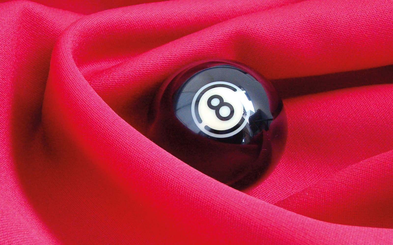 A black eight ball nestled in folds of red fabric