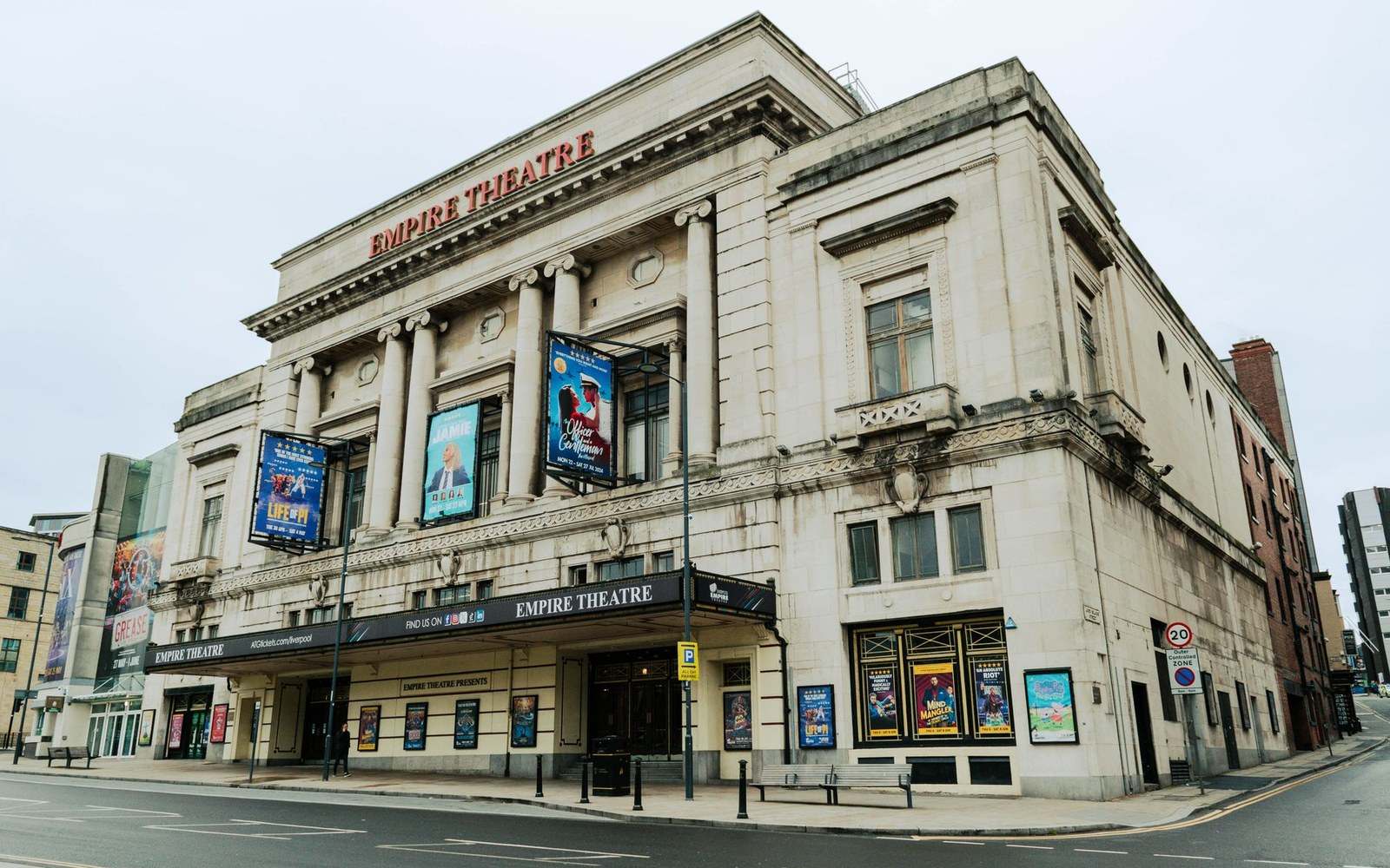 Empire Theatre's stone facade and marquee on a corner street with show posters displayed