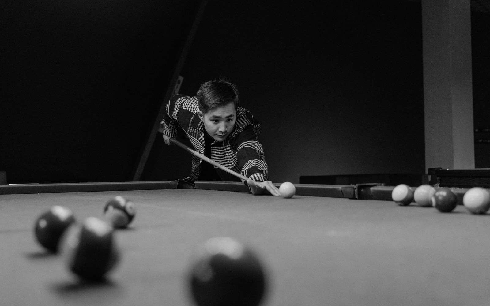 Man leaning over a pool table lining up a shot with a cue