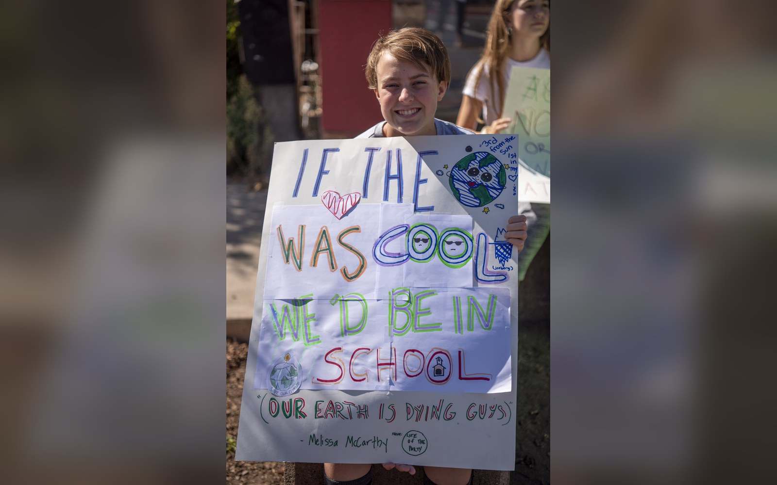 Teen holds a handmade sign joking about climate change during a school strike protest