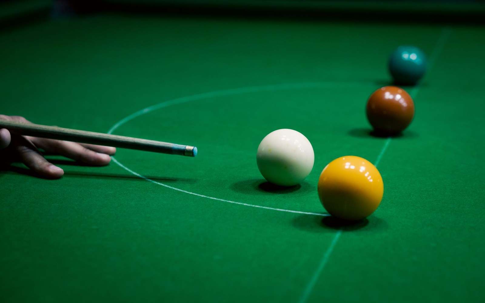 A player lines up a cue shot near the white and yellow snooker balls