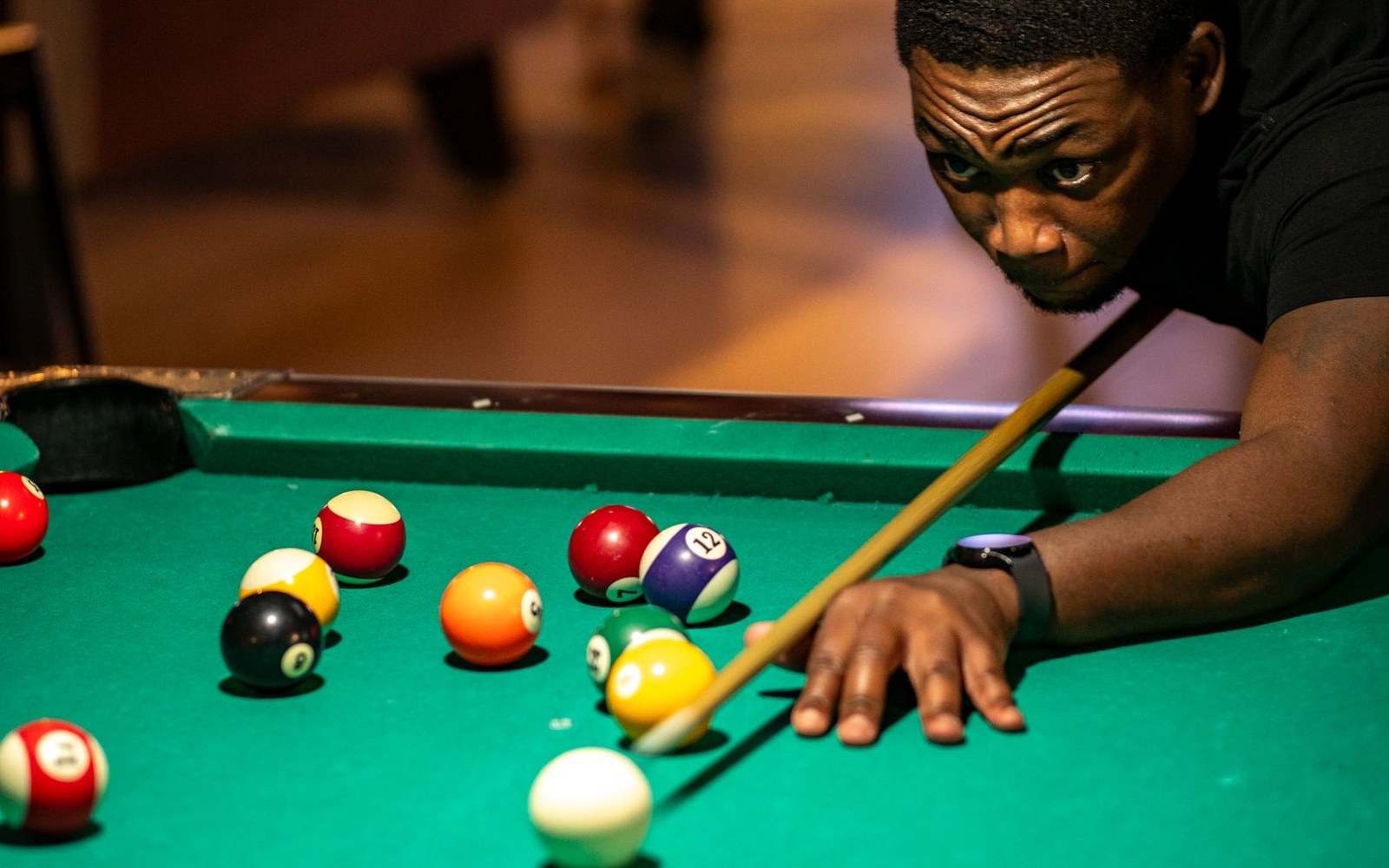 Multiple snooker tables running simultaneously in a sports-hall qualifying venue, sparse spectators, strip lighting
