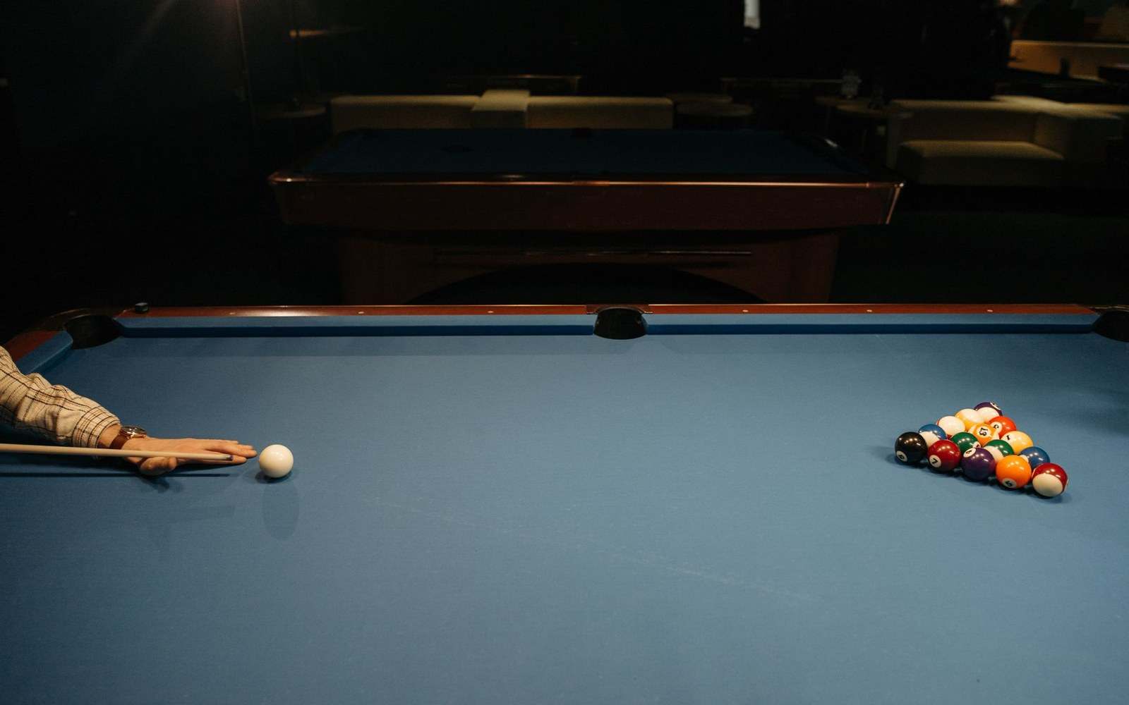 A wall-mounted rack of snooker cues in a club room, strip-lit, no crowd